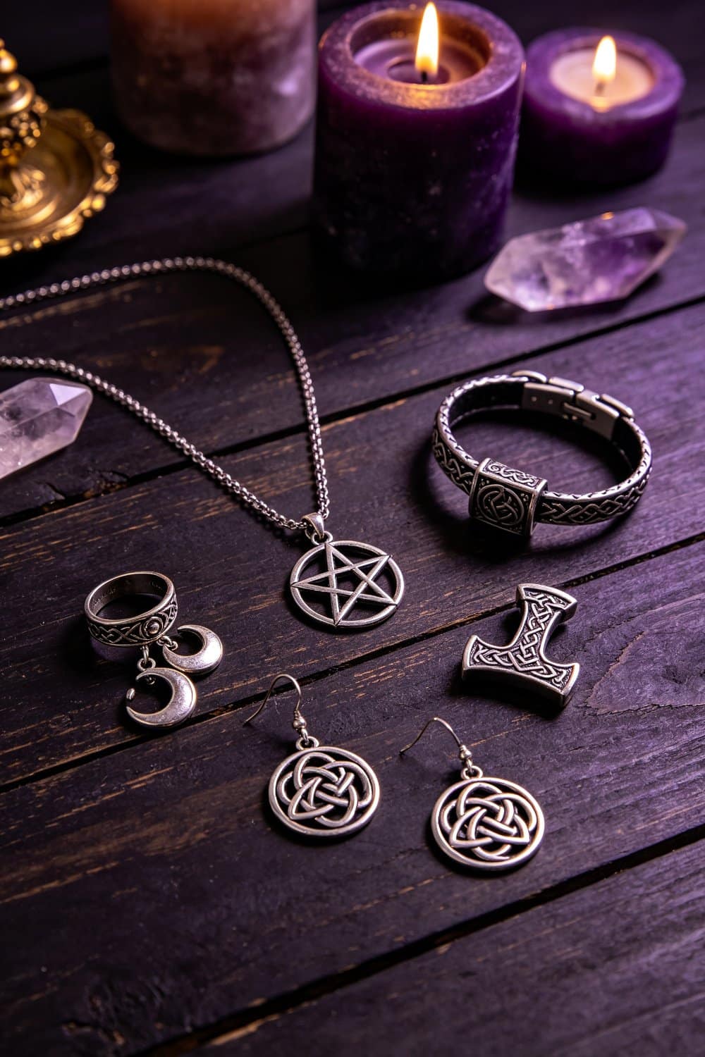 Pagan jewelry collection with pentagram necklace, viking mjolnir bracelet, gothic ring and wiccan earrings on dark wooden table